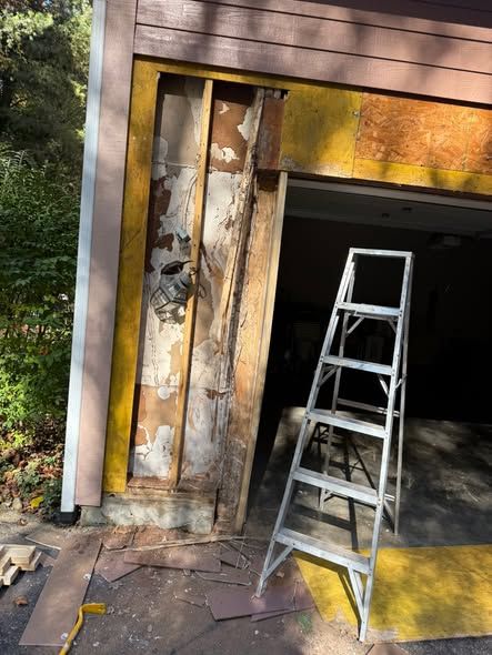 Rotted framing exposed beside a garage door
